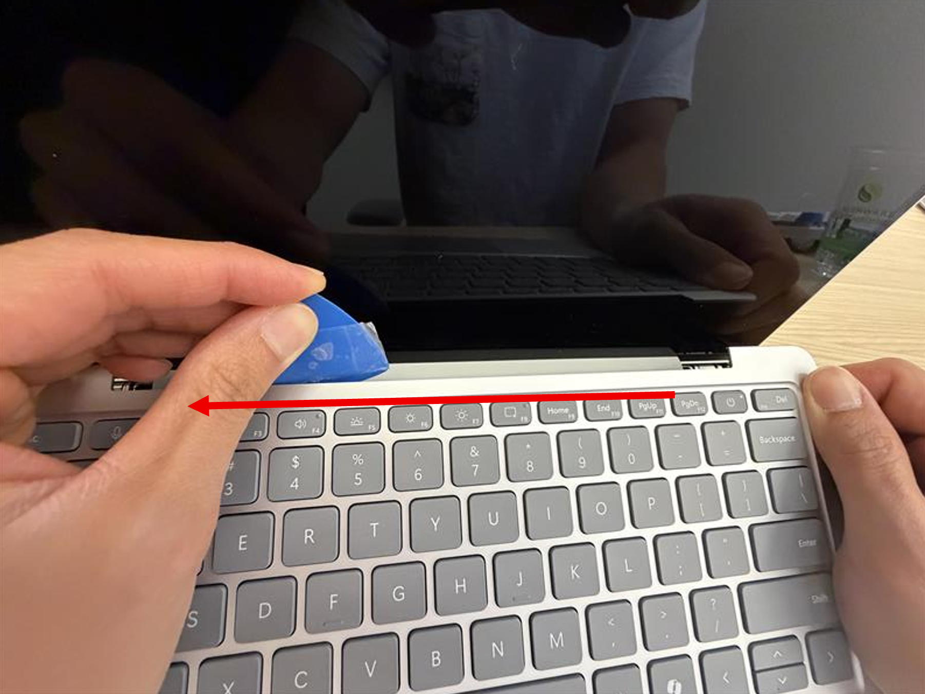 Photo that shows the guitar pick being slid from right to left along the C Cover seam while the C Cover is lifted with the other hand.