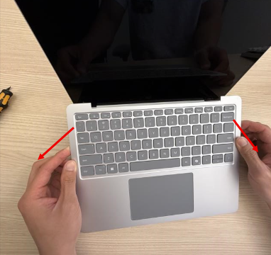 Photo that shows the C Cover Keyset being gripped and gently lifted upward to disengage the remaining snaps along the bottom edge.