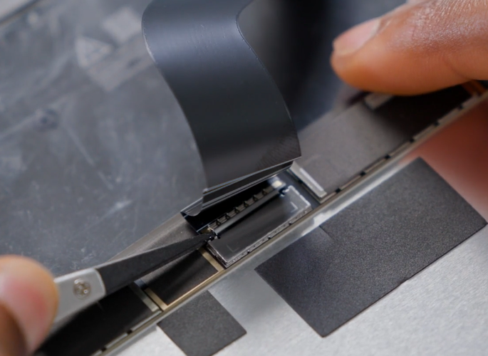 Screenshot that shows removing the shield lid over the display connector with fingers.
