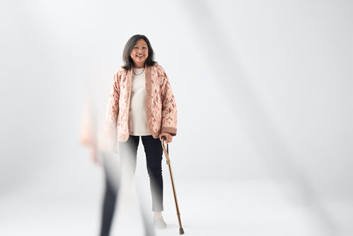 Photograph showing woman  standing holding a walking cane.